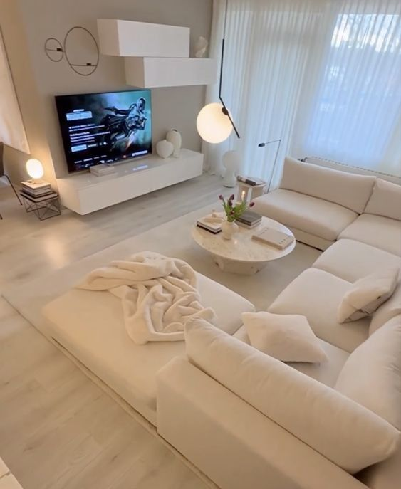 Canapé en U blanc avec méridienne, coussins assortis et assises sur-mesure, dans un salon lumineux à la décoration minimaliste.