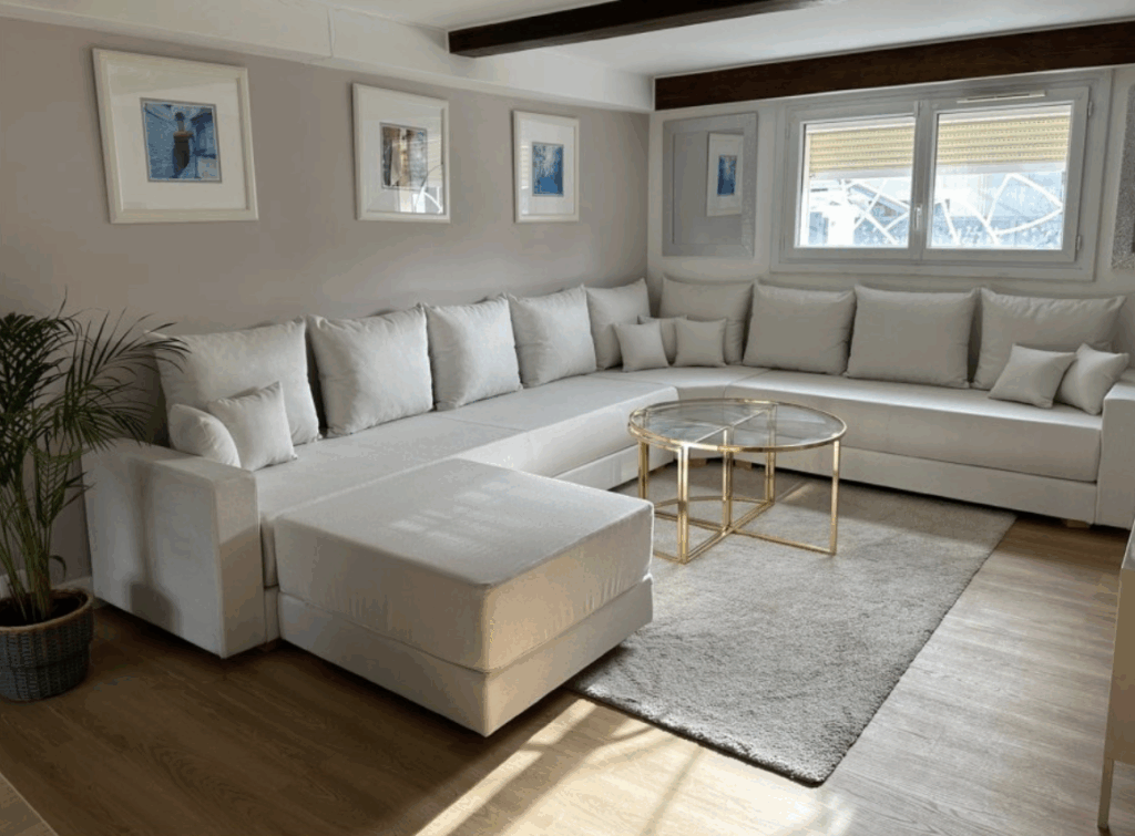 Canapé en U conçu sur mesure, sans dossier et avec accoudoirs. Habillé du tissu Dream Ivory. Modèle sur-mesure signé moncanapemarocain.