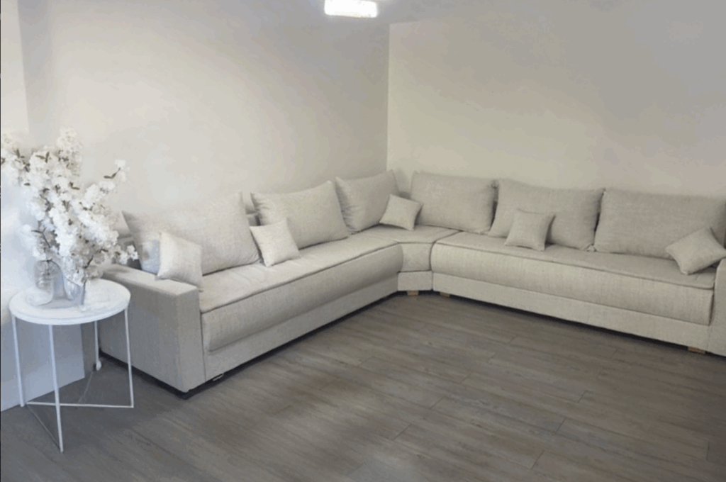 Ce salon épuré signé moncanapemarocain est composé d'un canapé d'angle en Oasis Natural ; un tissu bouclette blanc cassé, ainsi que des sur matelas et des coussins décoratifs. 